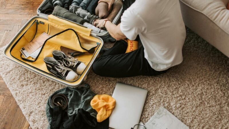 Man packing clothes and footwear into suitcase for travel.